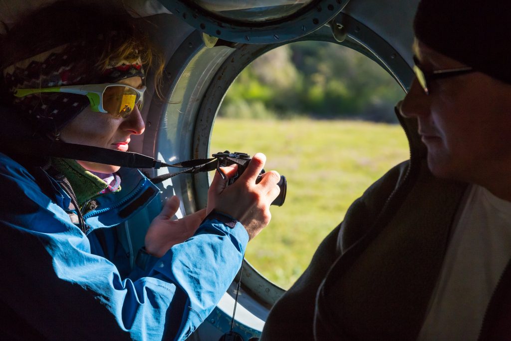 Woman Taking Photos Through a Helicopter Window- What to Wear on a Helicopter