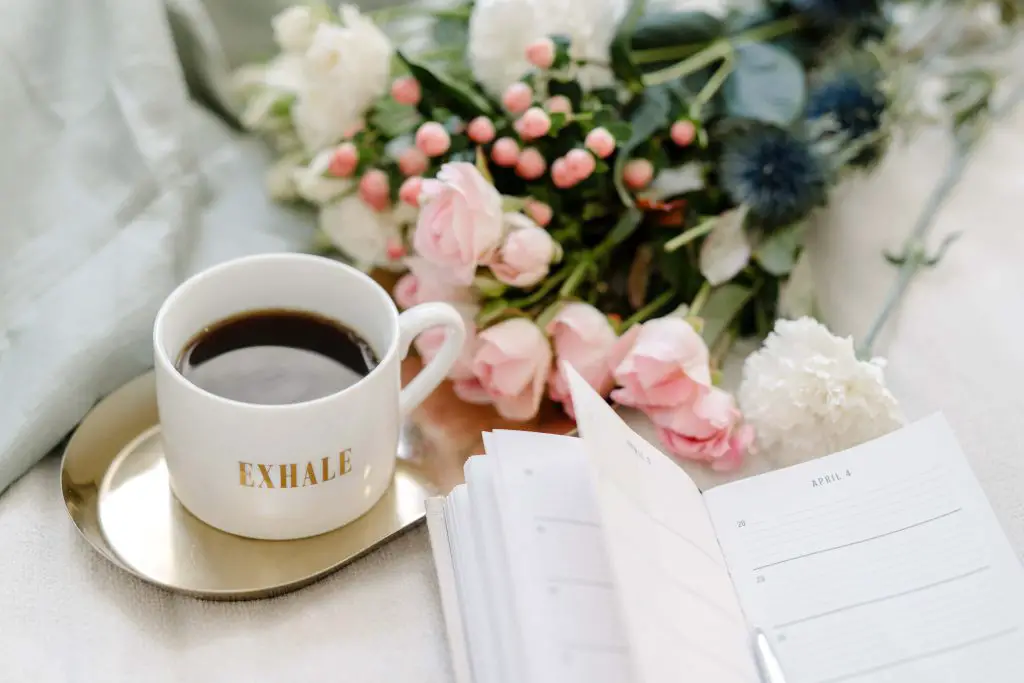 Black coffee with Light Pink Flowers and a planer for morning routine ideas. 