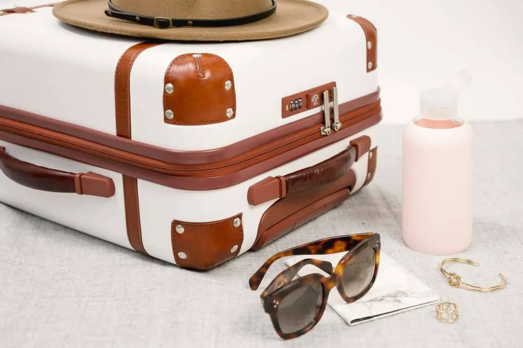 A travel suitcase with a hat, sunglasses, and water.	