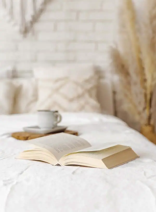 An open book on a bed with a cup of coffee, exploring spiritual awakening.